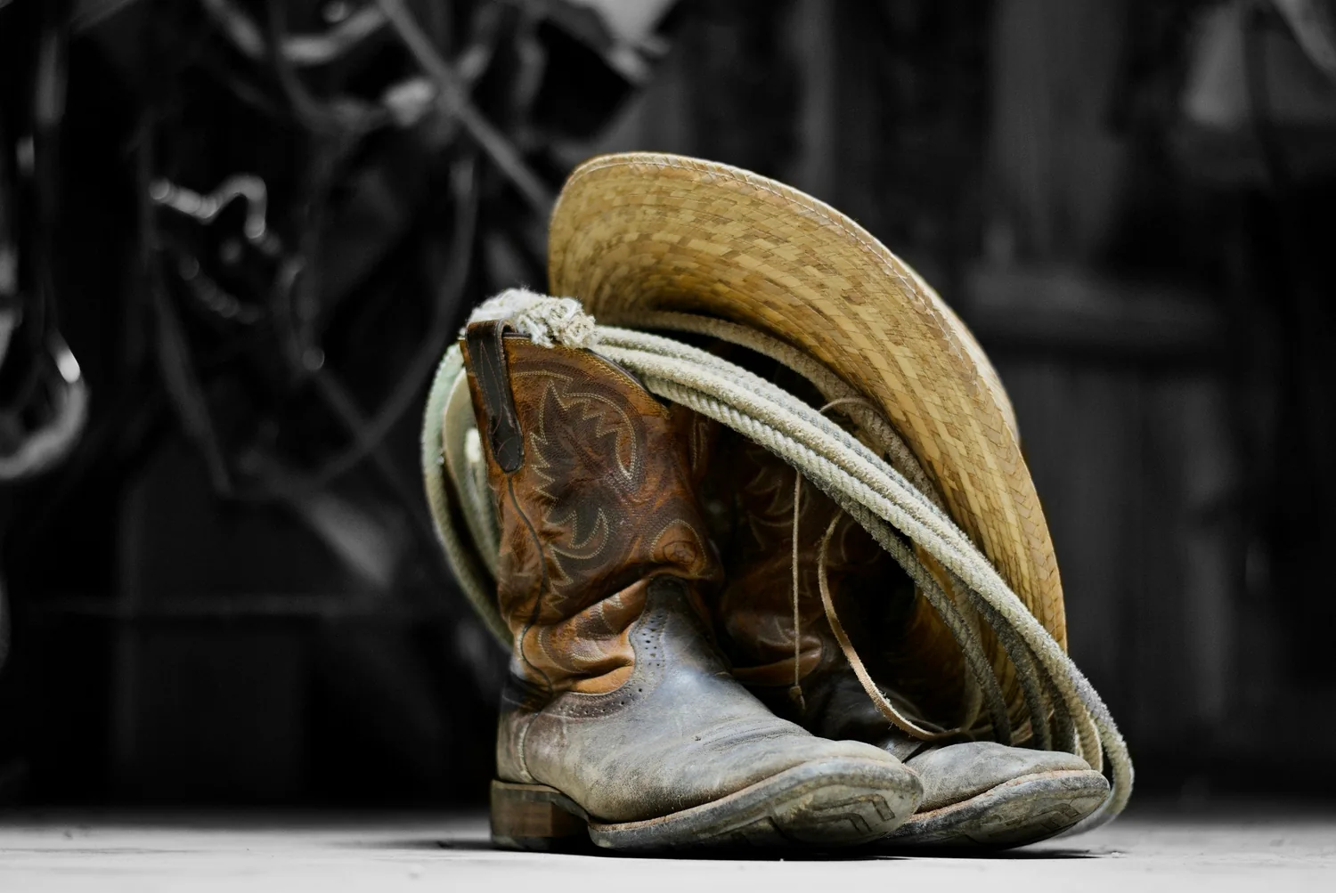 Well-worn boots, hat, and rope in a rural work setting