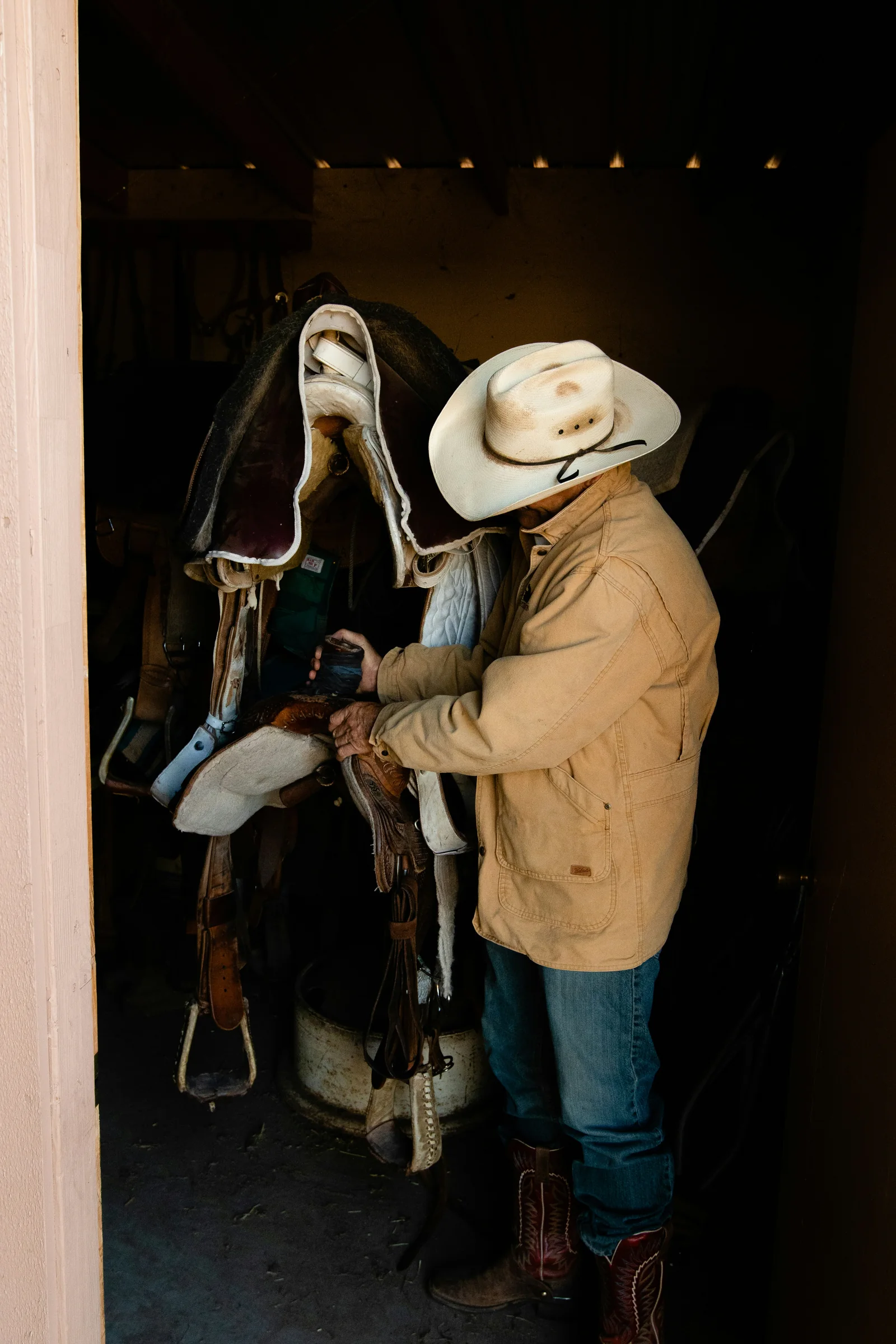 Rancher readying tack in the barn