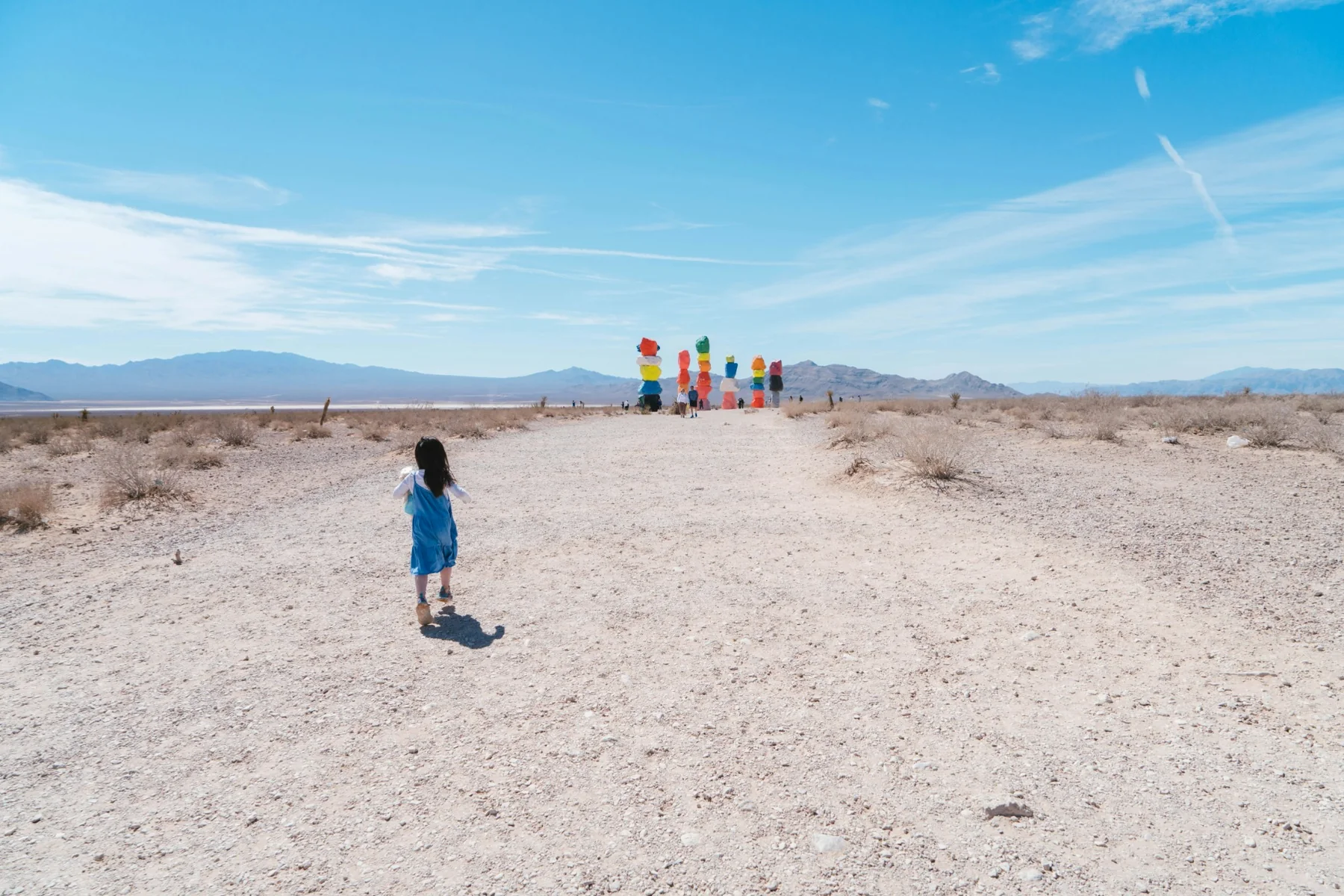 Child walking across the Southern Nevada desert toward Seven Magic Mountains